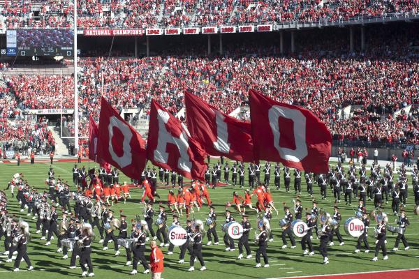 Picture of cheerleaders running with OHIO flags at an OSU football game